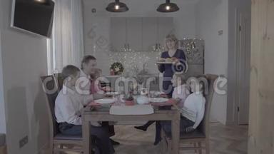 快乐可爱的四个孩子一家人庆祝新年厨房餐桌父亲儿子女儿笑妈妈端饭